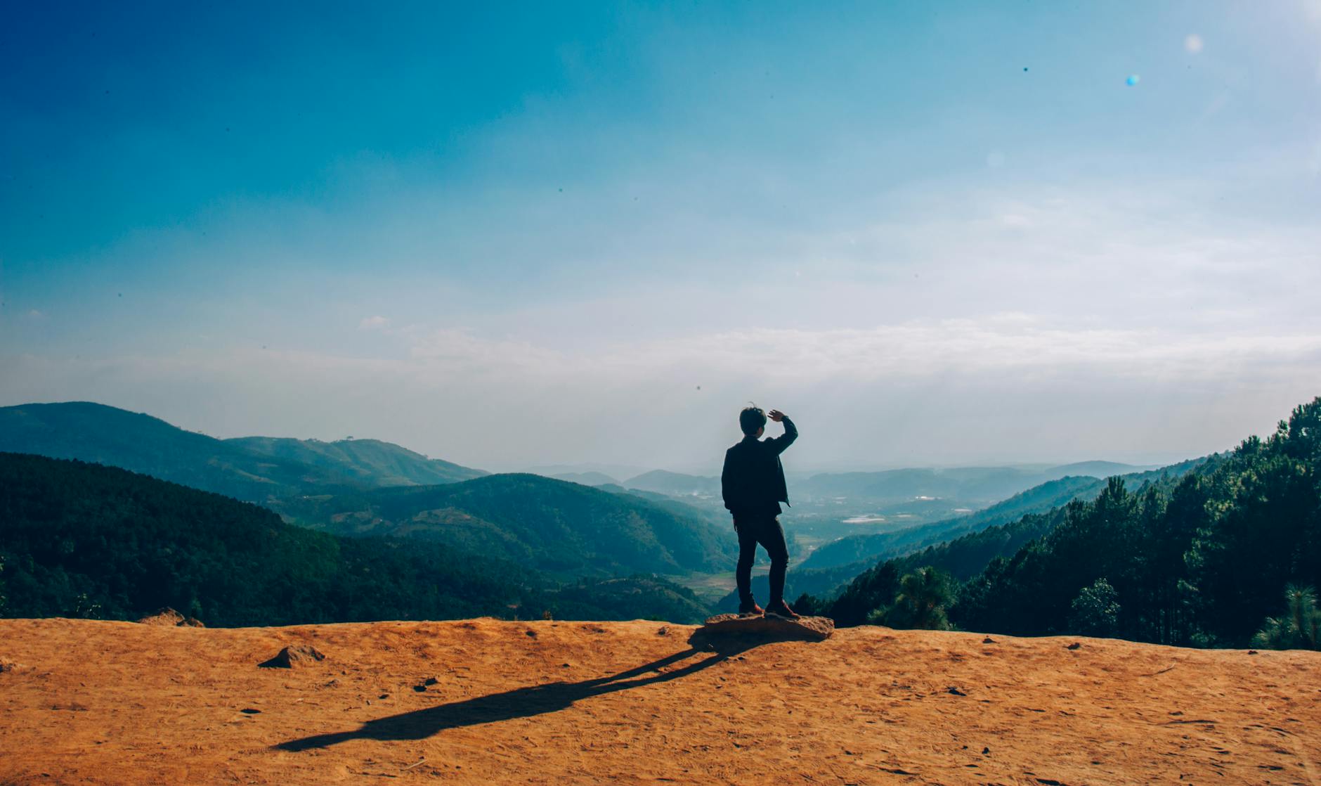 silhouette of man standing on mountain cliff